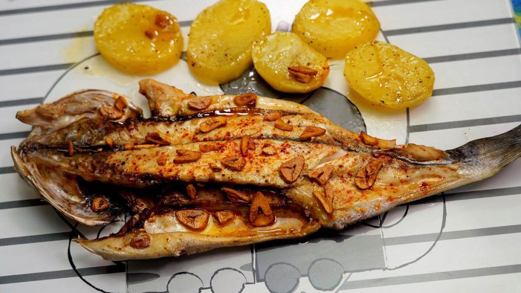 Lubina a la espalda. Una deliciosa receta muy fácil de hacer en casa y de forma muy rápida. La lubina es un pescado muy saludable que tiene muchísimas formas de cocinarse. Lo que vamos a hacer en esta ocasión es asarlo junto con unas patatas panaderas que hará la vez de cama del pescado. Al añadirle al final un poco de ajo troceado con aceite hace que el resultado de este plato sea... ¡delicioso!